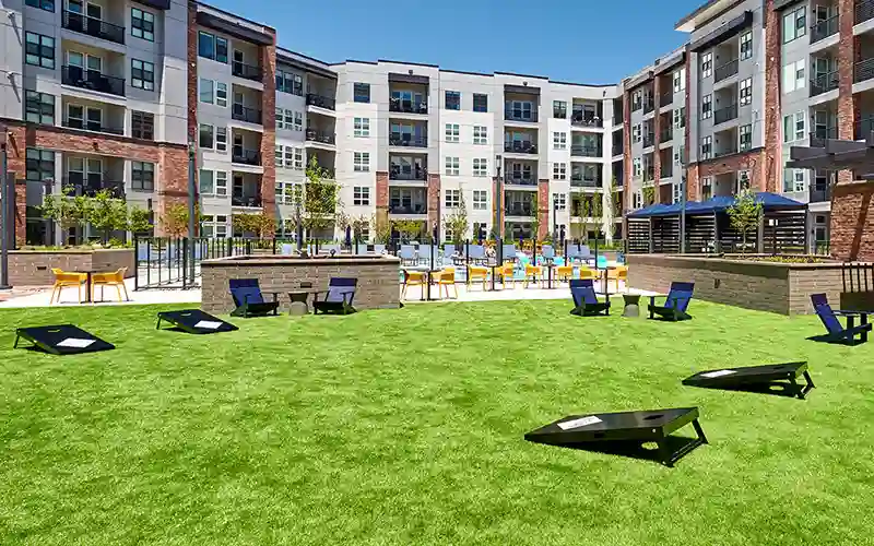 SYNLawn artificial grass at an apartment complex with lawn chairs and corn hole boards